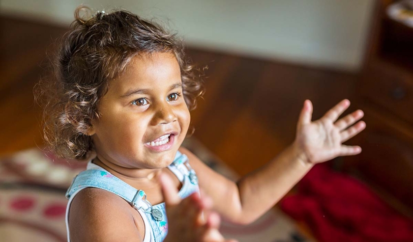 Happy singing and dancing young Australian Aboriginal girl playing