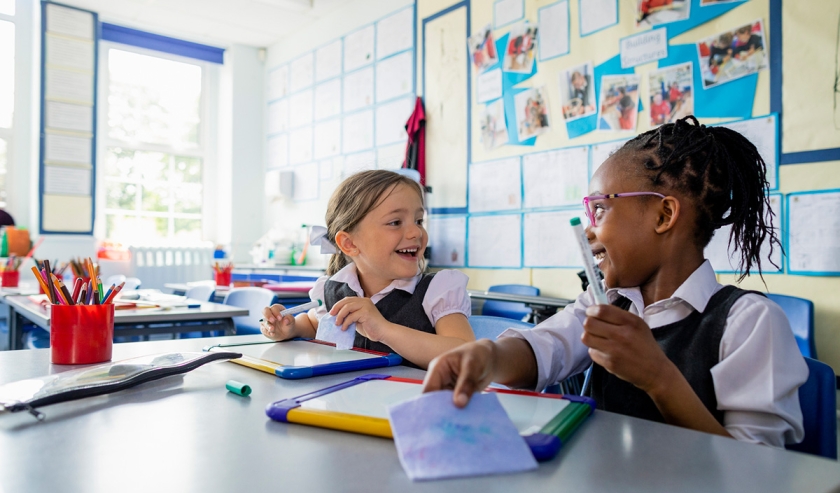 Two children laughing together in a school classroom