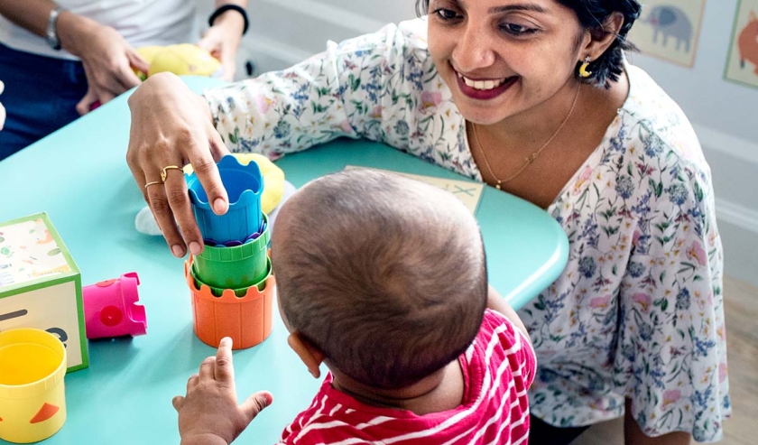 Child building blocks with a teacher in the nursery