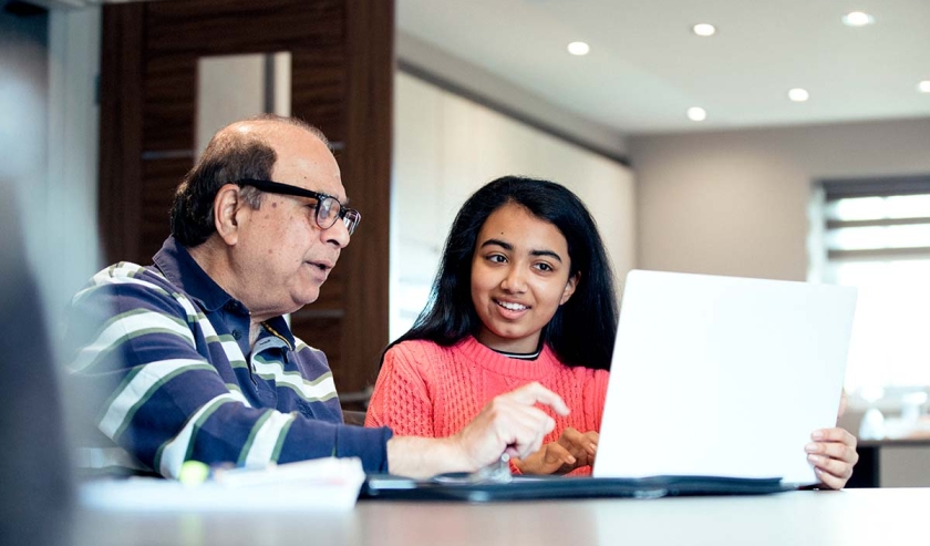 Woman showing older man how to use computer