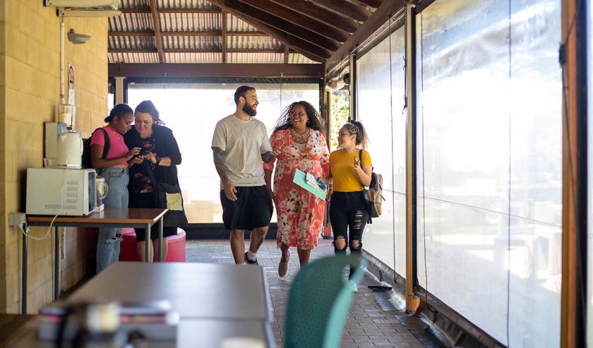 Young aboriginal students walking through their university building together. One of the students is talking to her tutor.