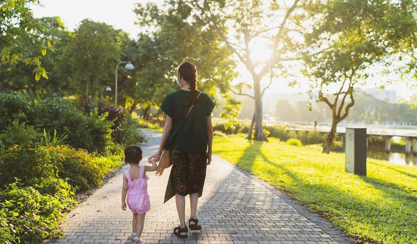 Asian toddler taking small steps and holding on to mother's hand for support 