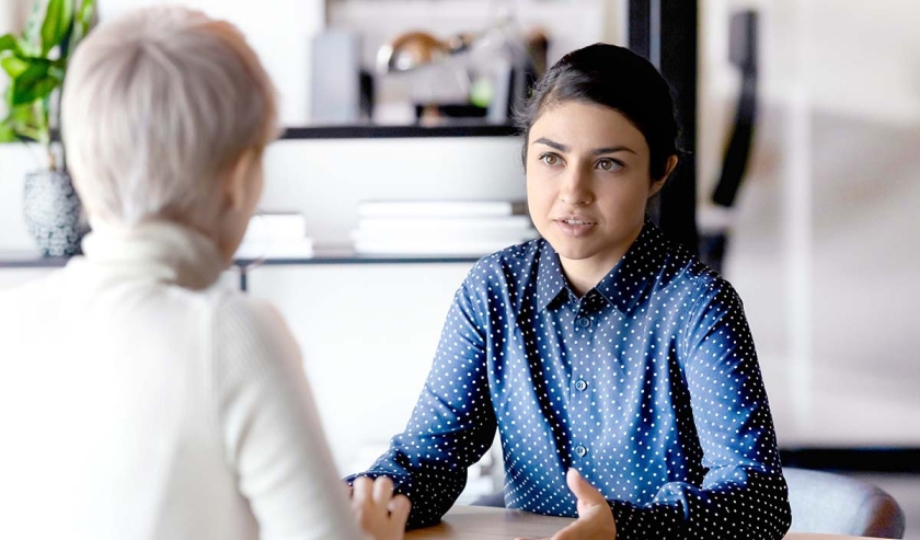 Multi ethnic indian and caucasian diverse young businesswomen sitting in front of each other in office during business meeting. 