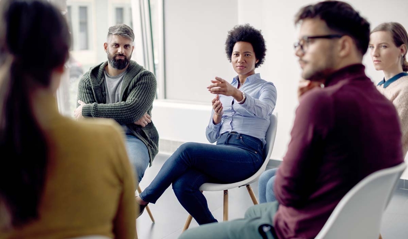 African American professional leading a focus group and pointing at one of the participants.