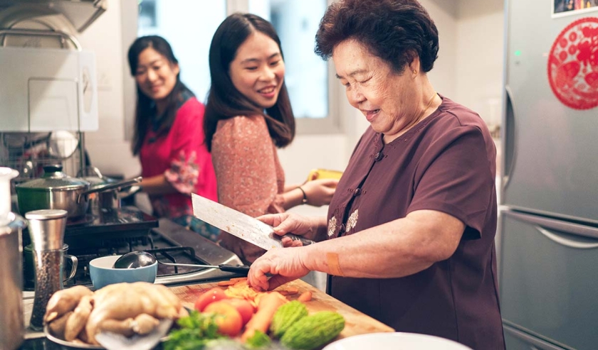 Females from a multi-generation Asian family in a kitchen during the preparation of reunion dinner