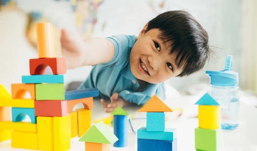 Smiling child playing with bricks