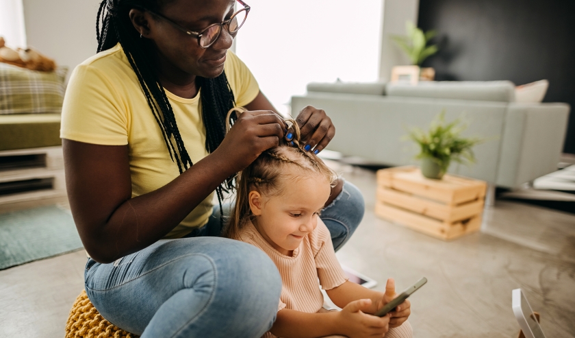 Little girl getting her hair twisted by her mom