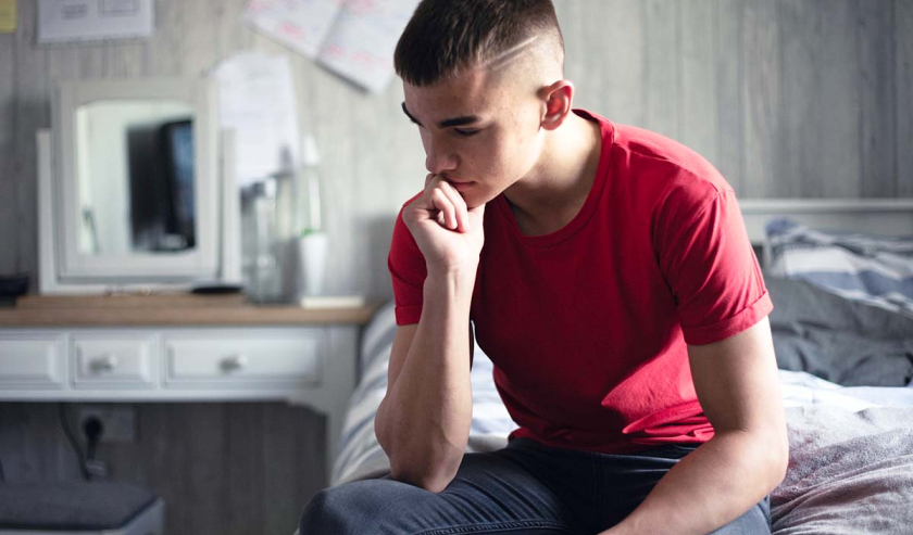 Young man in kitchen sitting thinking
