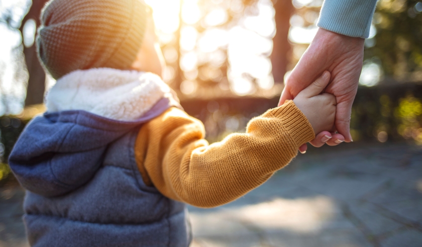 Young child holding hands with adult carer