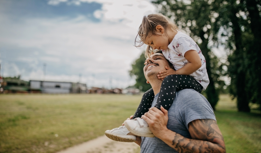 Caregiver carrying a young child on their shoulders