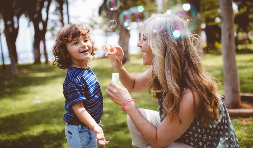 Woman blowing bubbles with young child