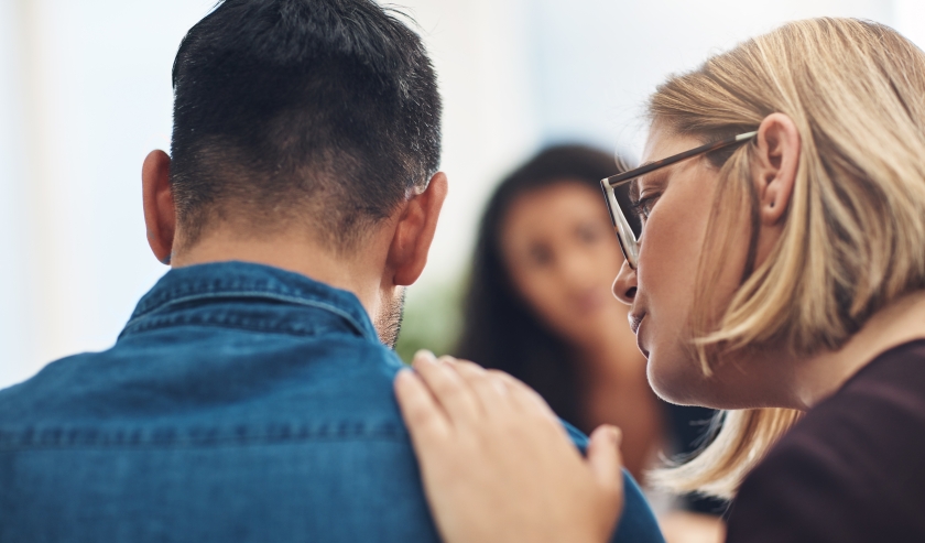 Therapist supporting participant with a hand on shoulder in a group therapy session