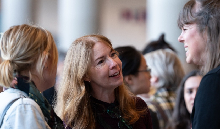 Women smiling and talking at a conference