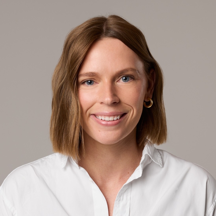 Caitlin has shoulder-length, light brown hair. Caitlin is wearing a white button-up shirt.