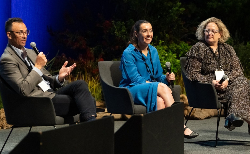 Three speakers on stage at a conference