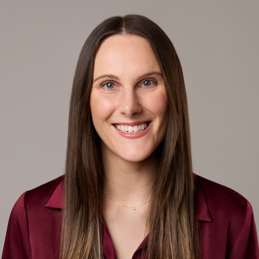 Kiersten has long, brown hair. Kiersten is wearing a burgundy coloured blouse.