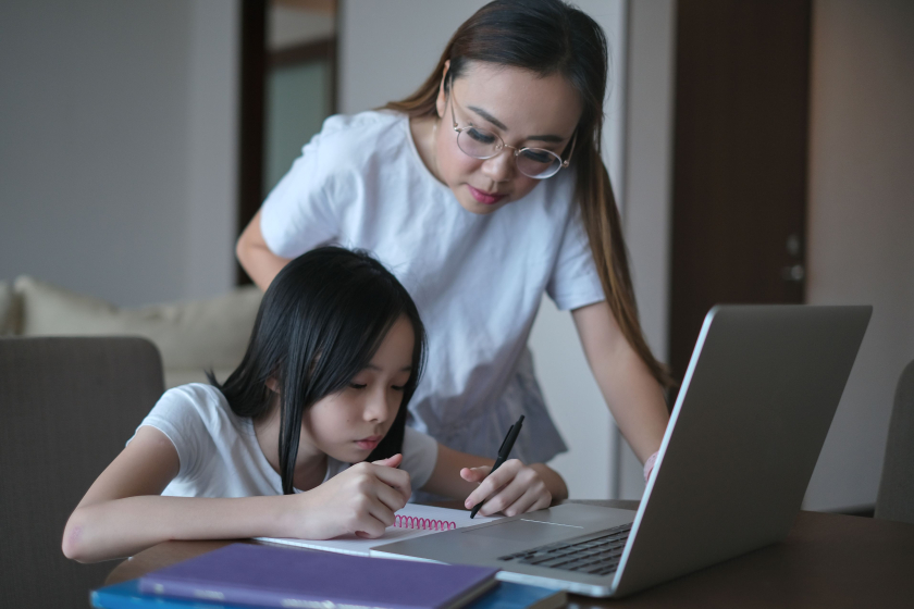 Mum talking with teen doing homework on laptop