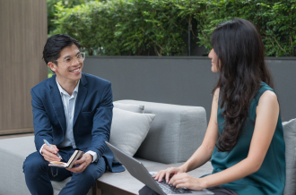 A man and woman discussing work over a laptop